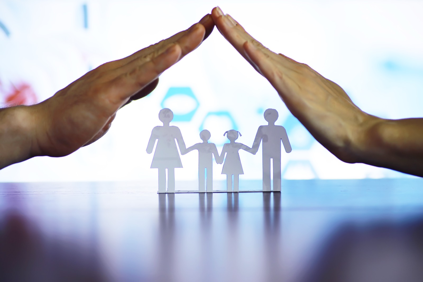 Hands forming a protective roof over a paper family — TruePolicy protecting Indian families